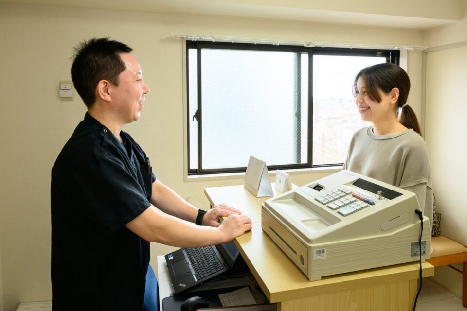 受付カウンターで来院者に対応する院長