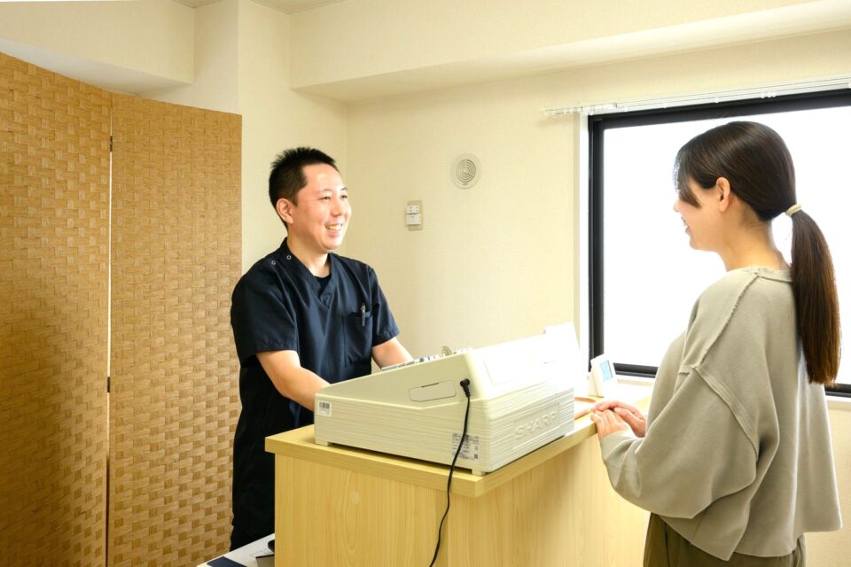 受付カウンターで来院者に対応する院長